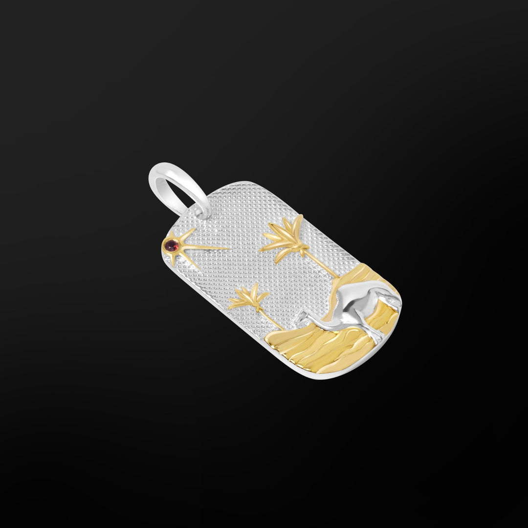 Close-up of the MCKER Sahara Pendant showing raised camel, dunes, palm detailing, and a 2mm garnet sun